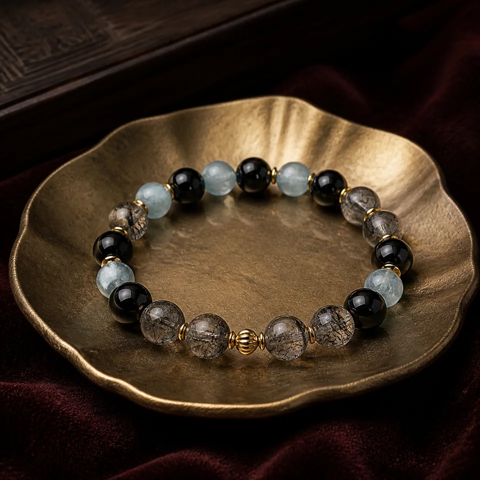 黑曜石、黑髮晶與海藍寶設計手鍊，置於深色絨布與香檳金托盤上